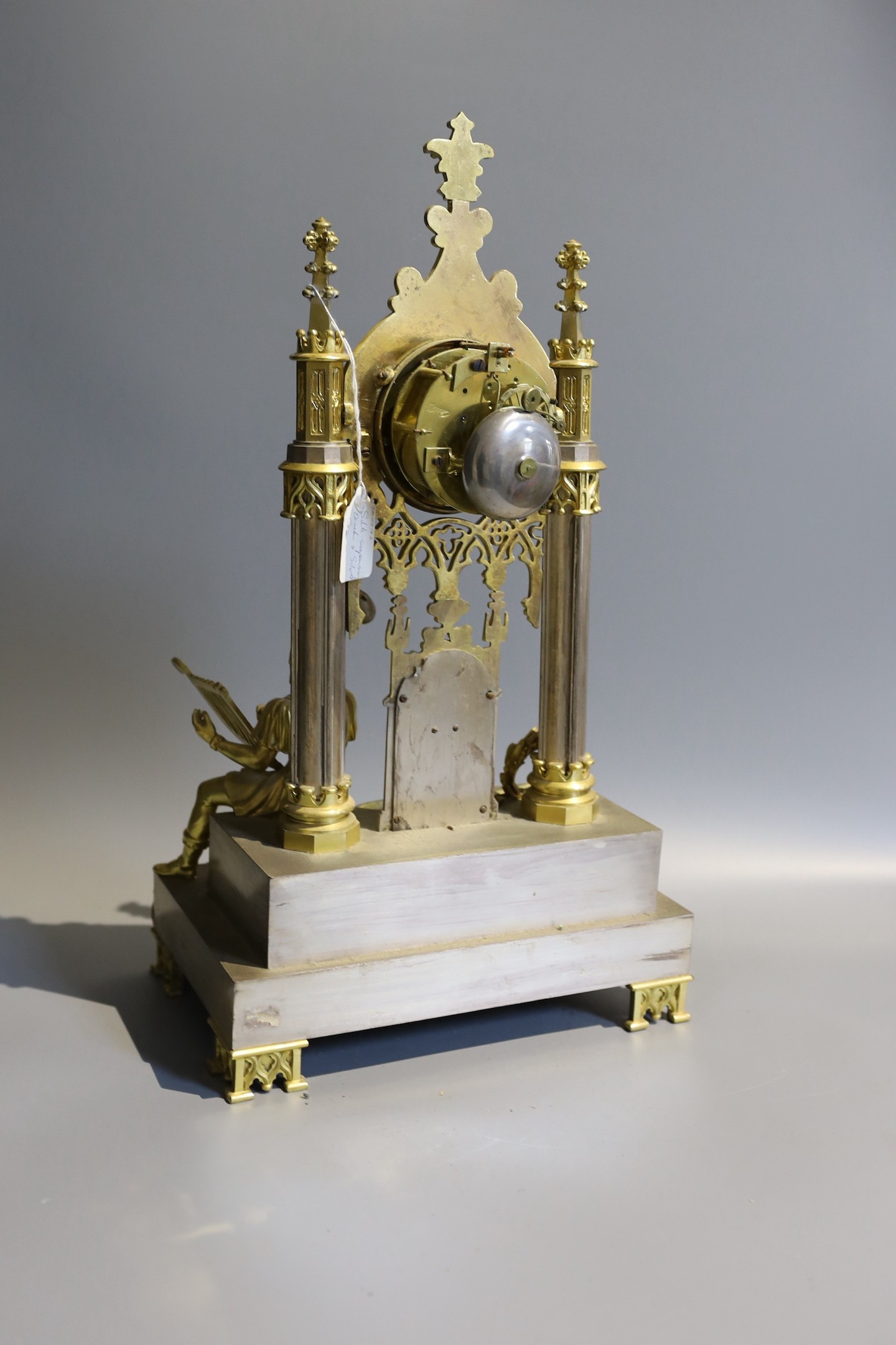 An early 19th century French silvered and gilt metal architectural 8 day mantel clock cast with a seated cavalier with lyre. Height 45 cms.